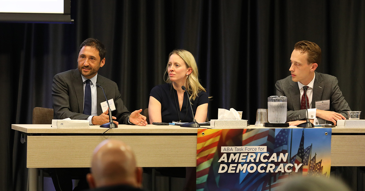 three people seated at a panel table with one speaking
