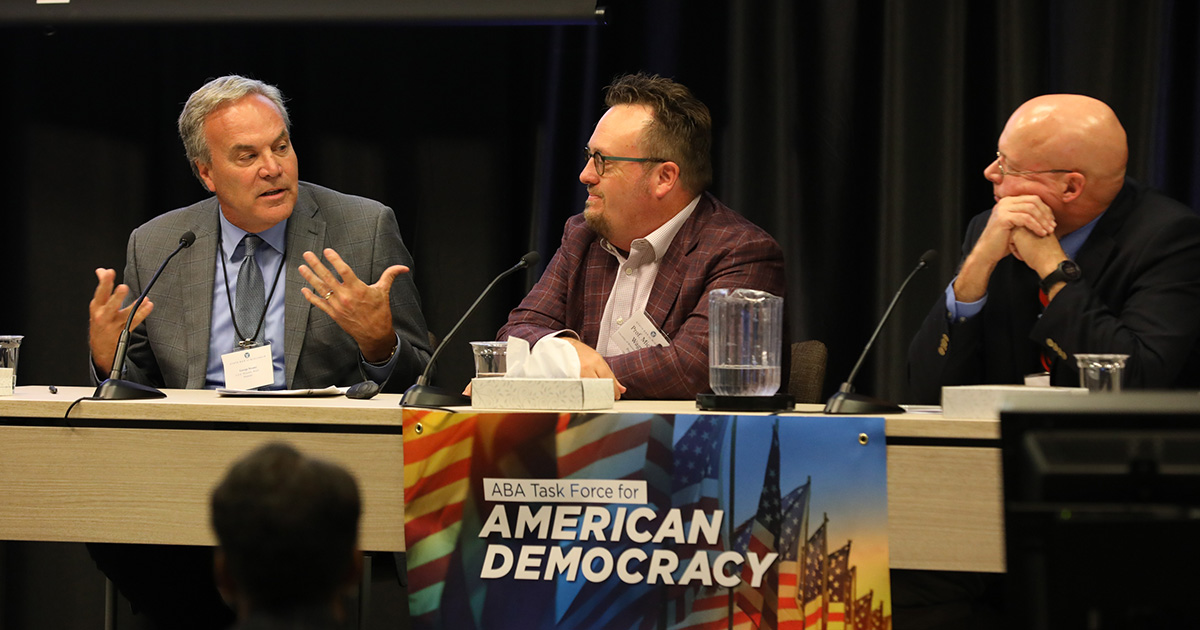 three people seated at a panel table, with one speaking