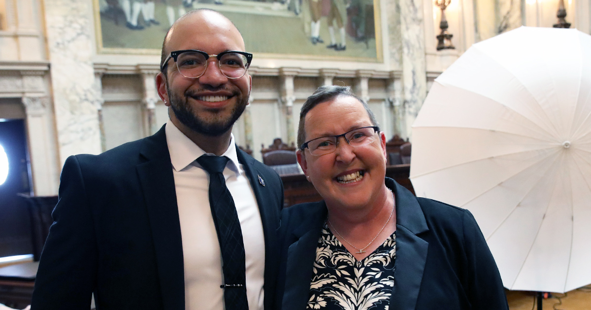 two people stand side by side smiling