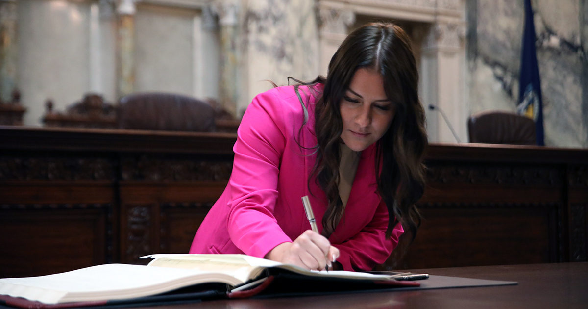 a person bends over a book, writing in it