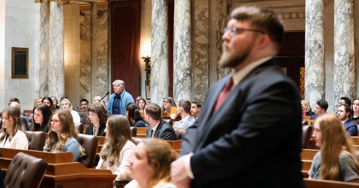 two people stand at a distance with seated people looking on