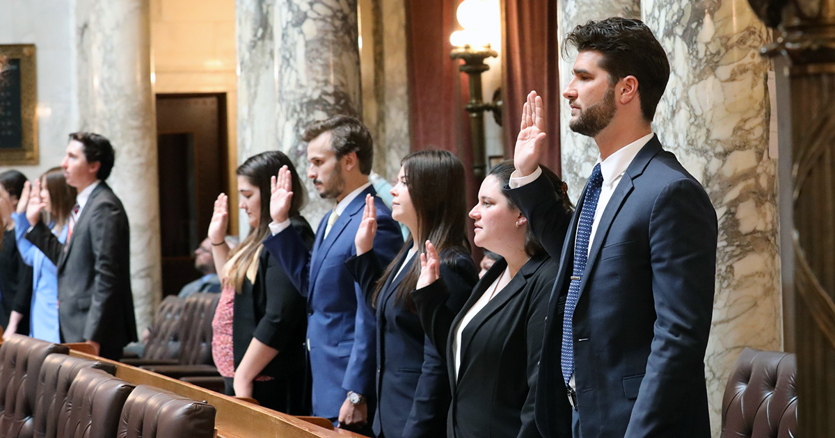 several people stand with hands raised to take an oath