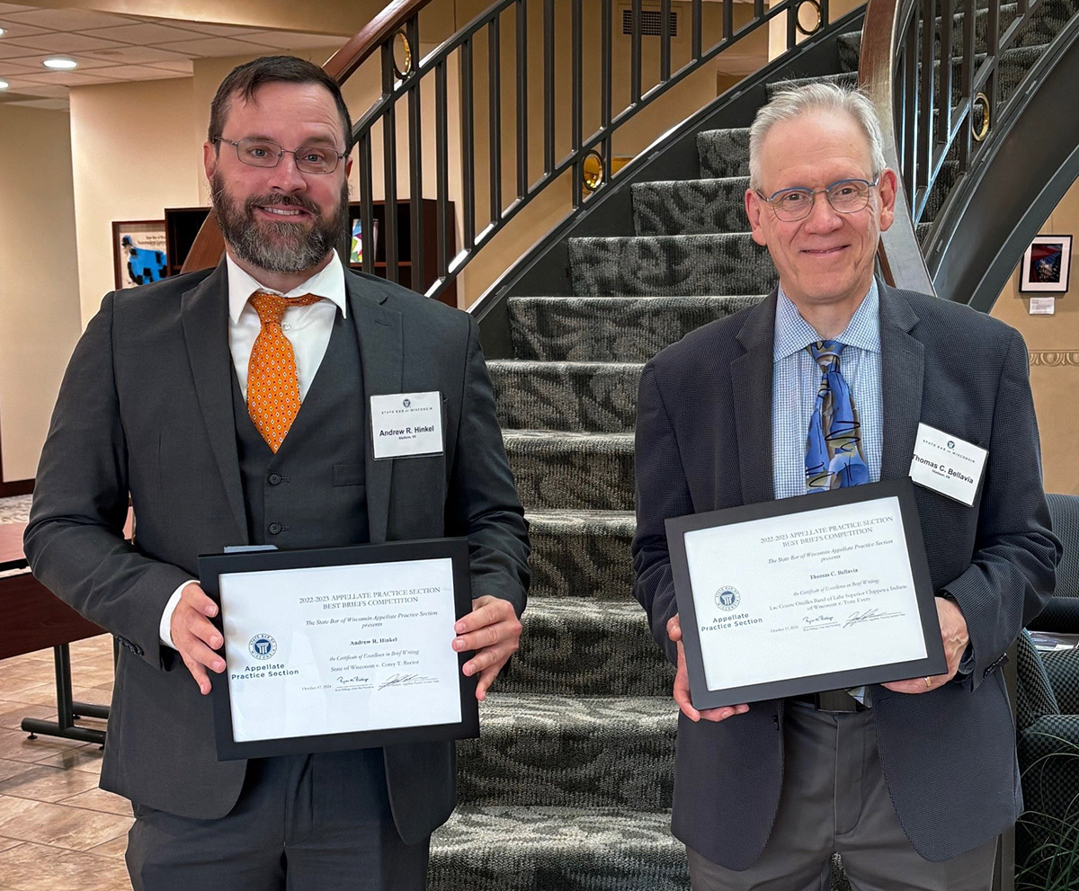 two men smiling at camera side by side holding certificates