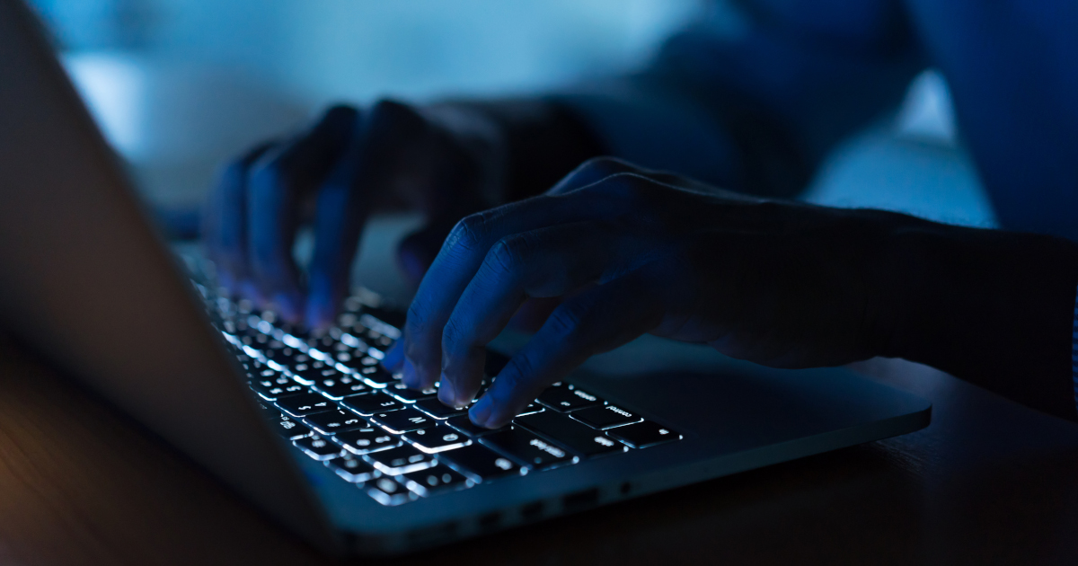 Mans Fingers Hover Over A Laptop In The Dark
