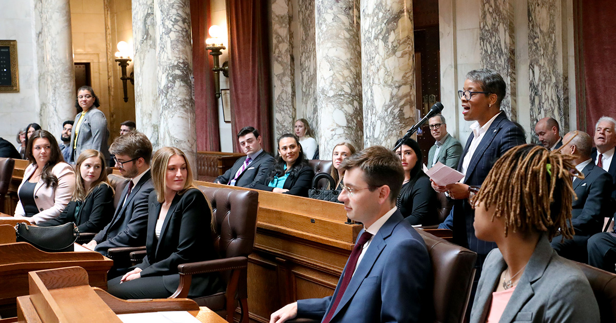 many seated people turn to look at a person at a microphone