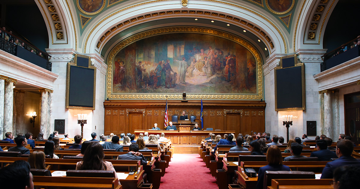 a photo of the Assembly Chamber showing people in seats on the floor and at the head of the room